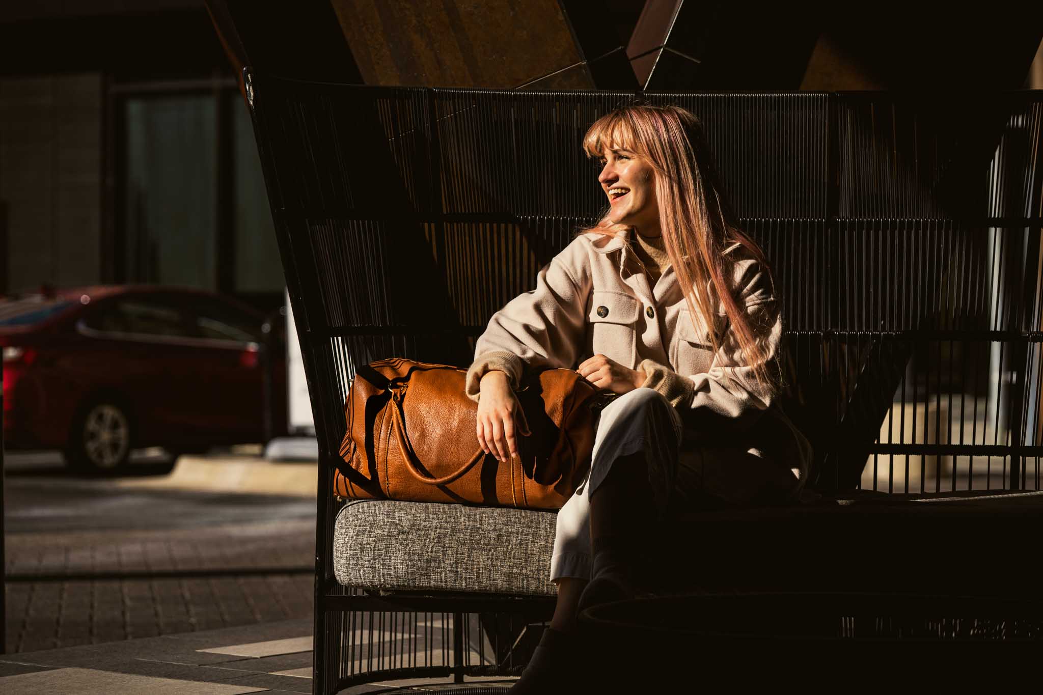 woman sitting on chair holding brown leather luggage bag