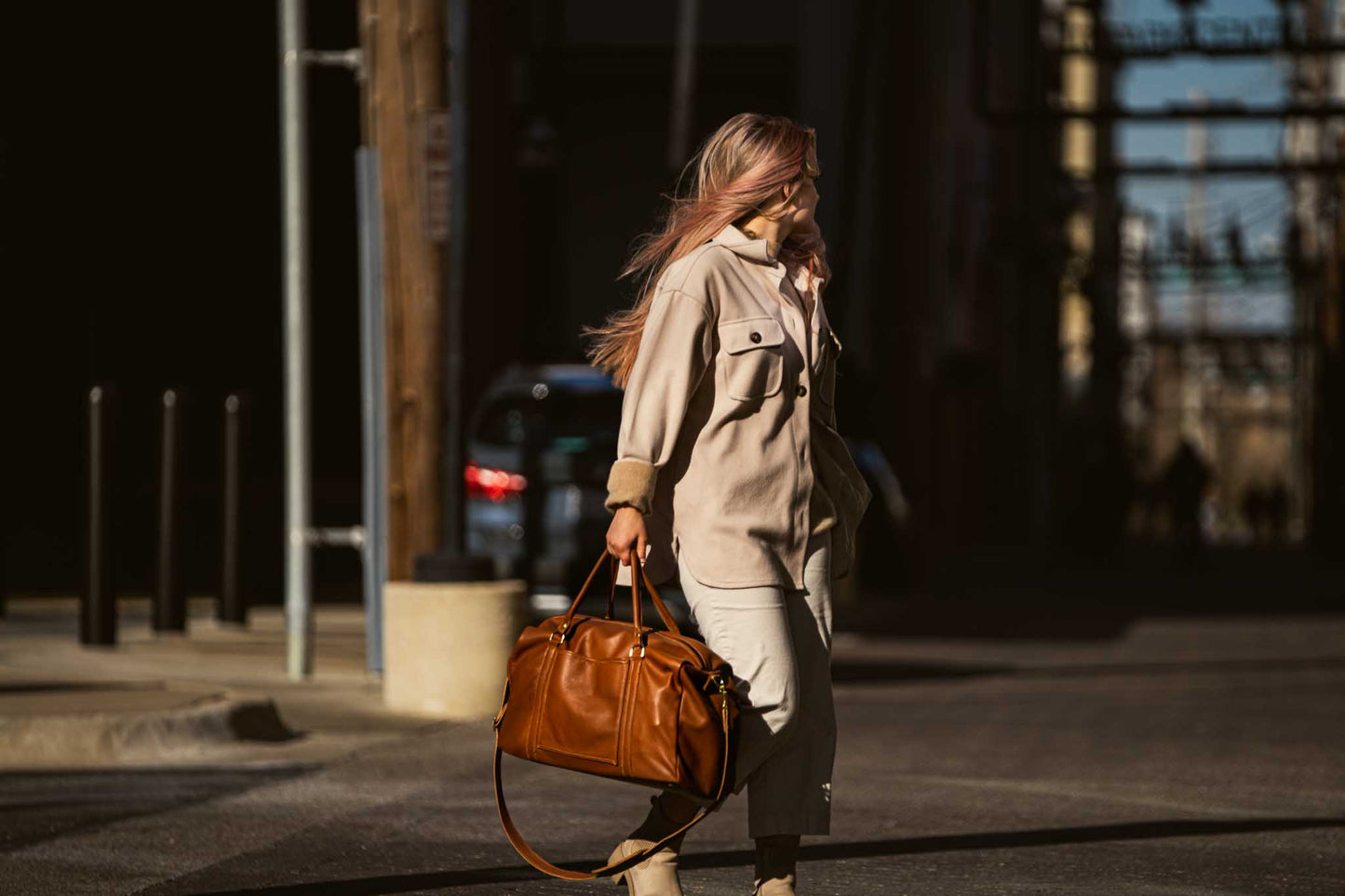 woman walking with light brown luggage bag