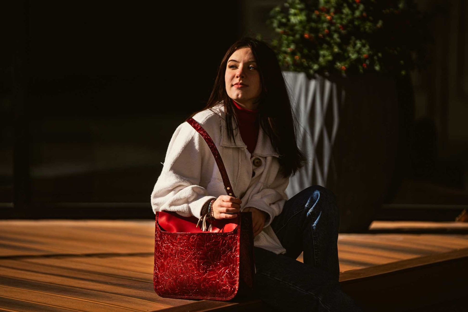 woman sitting outside with red leather purse