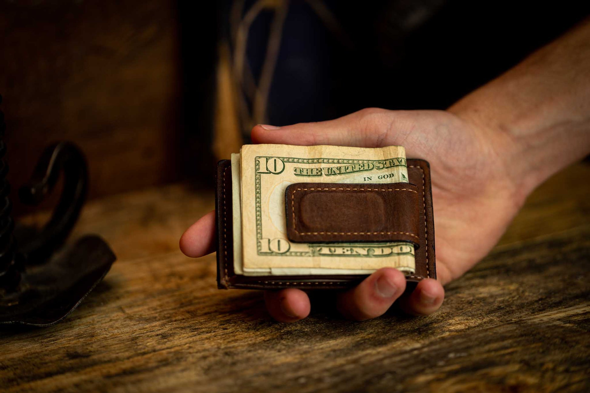 Hand holding brown leather money clip