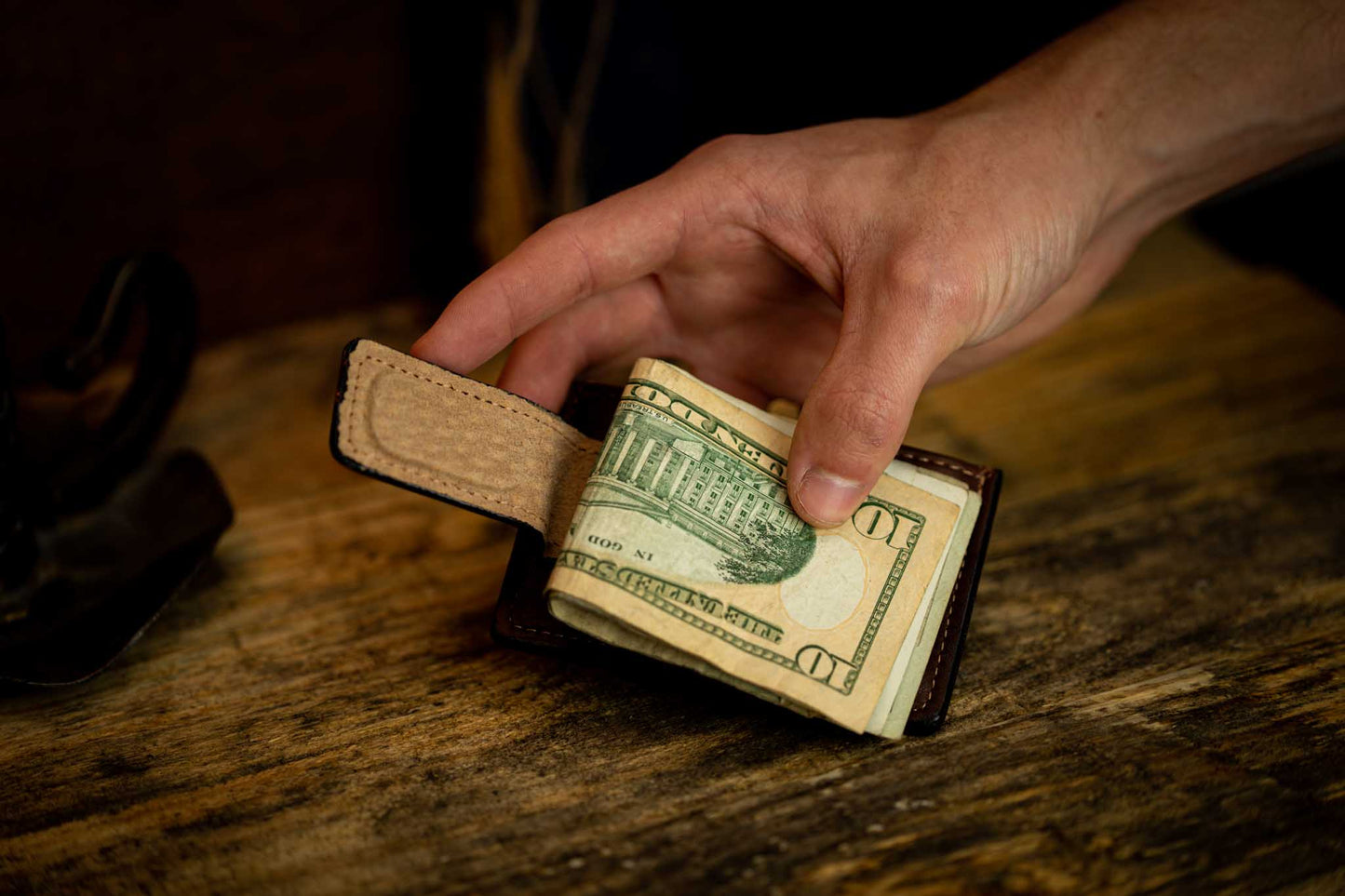 Hand holding brown leather money clip