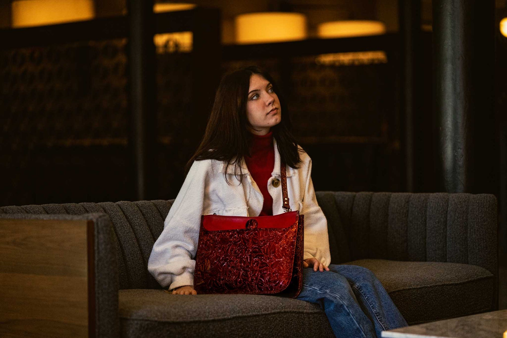 woman sitting on couch with red leather purse