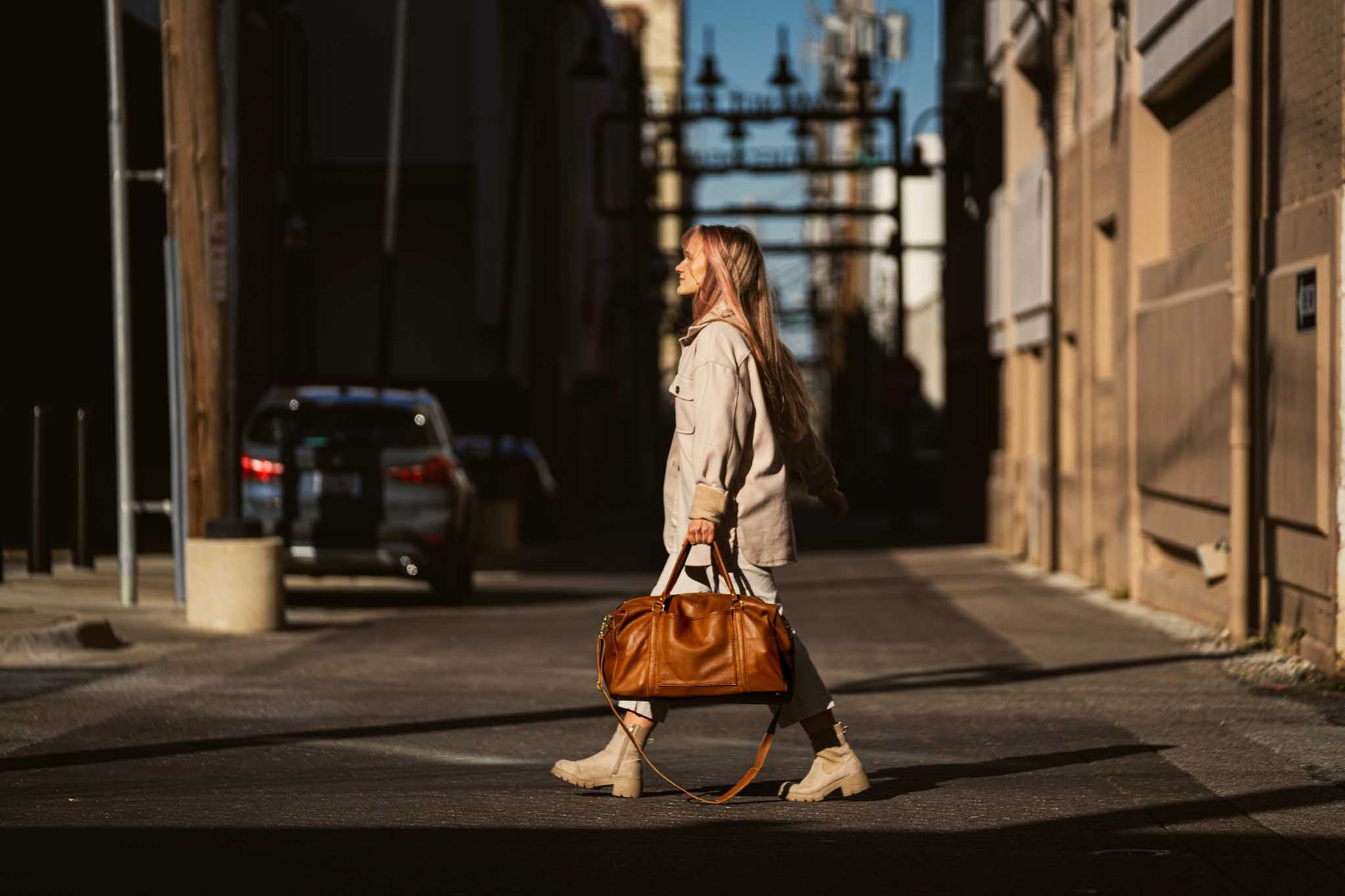 woman walking with light brown leather luggage bag